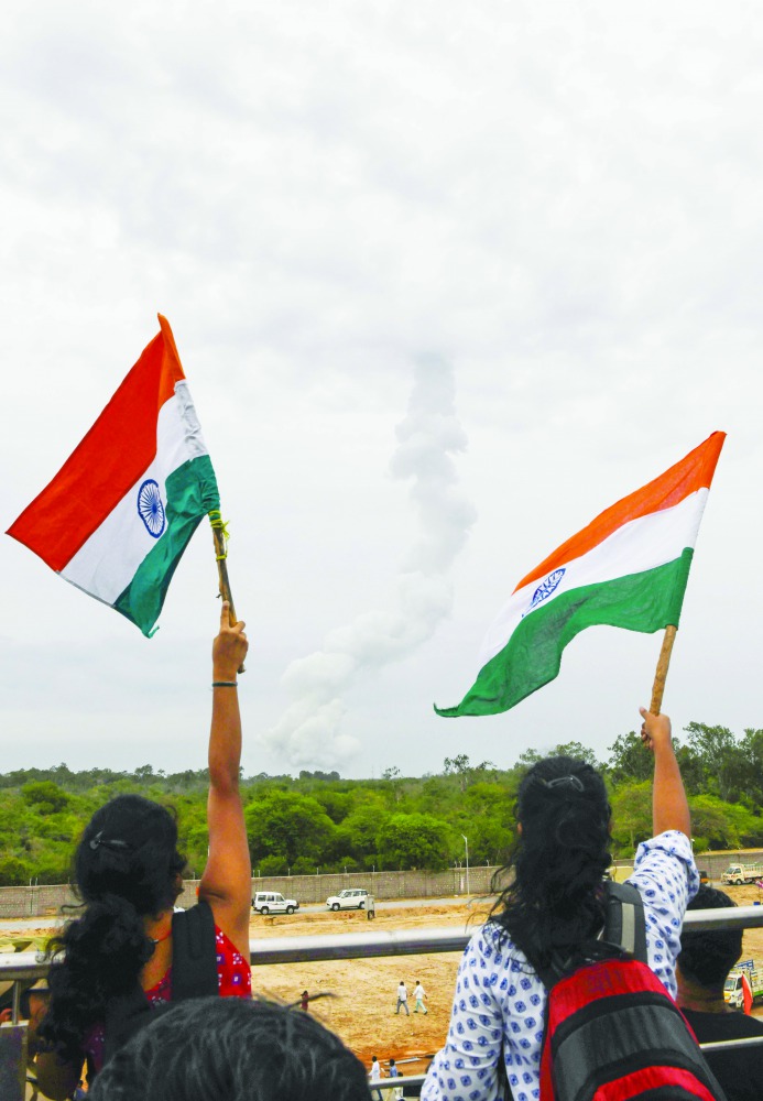 Residents wave Indian national flags as the Indian Space Research Organisation's (ISRO) Chandrayaan-2 (Moon Chariot 2), with on board the Geosynchronous Satellite Launch Vehicle (GSLV-mark III-M1), has been launched at the Satish Dhawan Space Centre in Sr