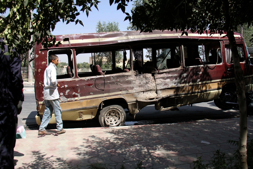 A boy walks past the wreckage of a bus following a suicide bombing in Kabul on July 25, 2019. (AFP)