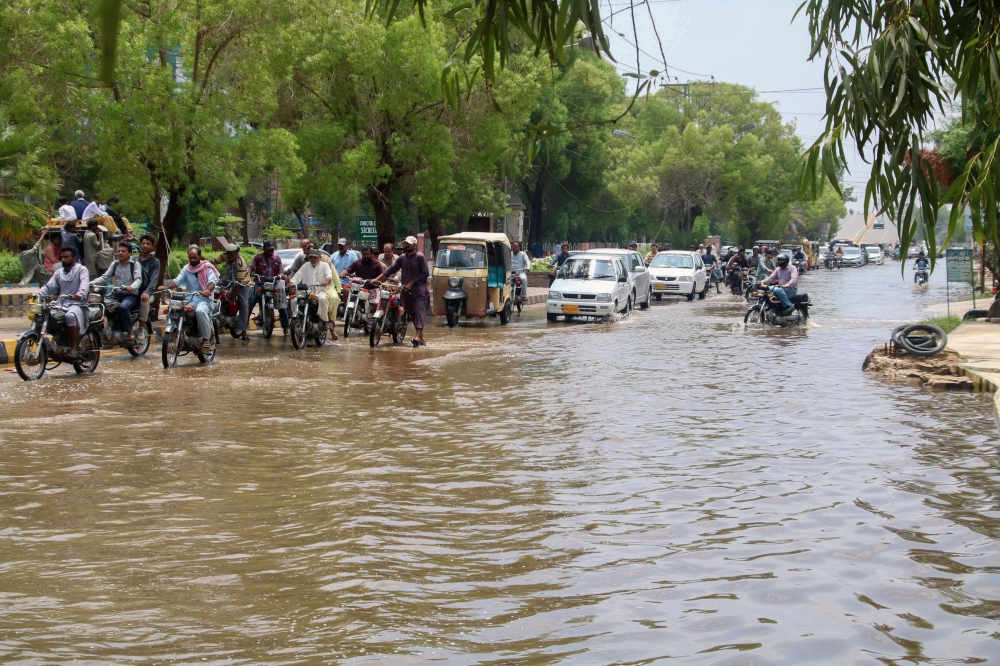 Commuters make their way on a flooded street after heavy monsoon rains in Hyderabad on July 31, 2019, some 160km east of the southern port city of Karachi. / AFP / AKRAM SHAHID
