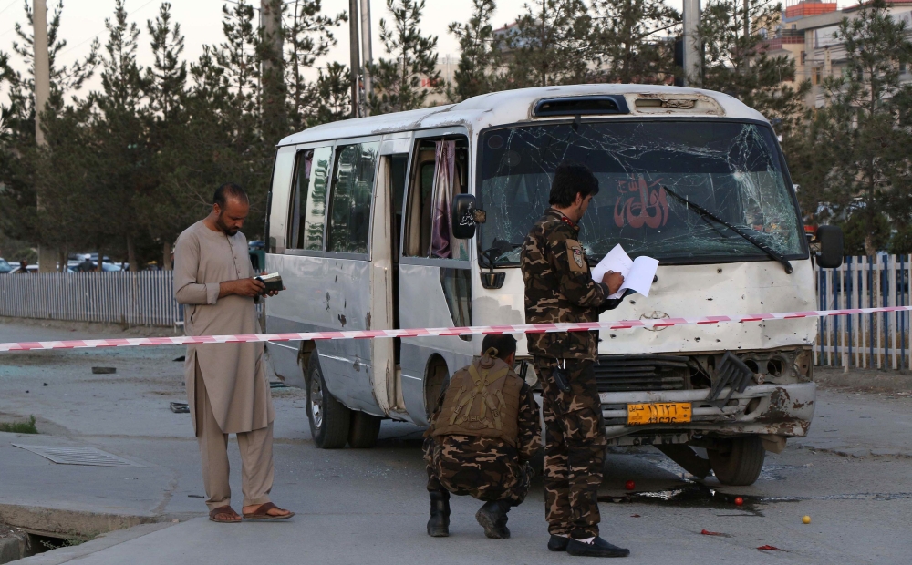 Afghan security personnel investigate a damage bus carrying employees of Khurshid TV, at the site of a sticky bomb blast in Kabul on August 4, 2019.   AFP / STR