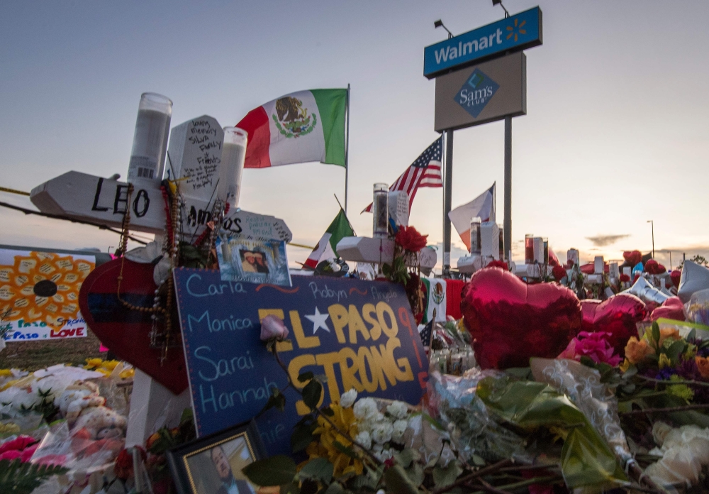 People pray and pay their respects at the makeshift memorial for victims of the shooting that left a total of 22 people dead at the Cielo Vista Mall WalMart (background) in El Paso, Texas, on August 6, 2019.AFP / Mark RALSTON