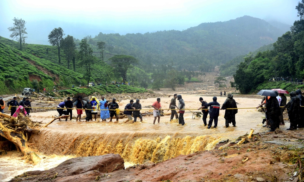 People walk through flood waters after a landslide in Meppadi, Wayanad district, in the Indian state of Kerala on August 9, 2019. (AFP)
