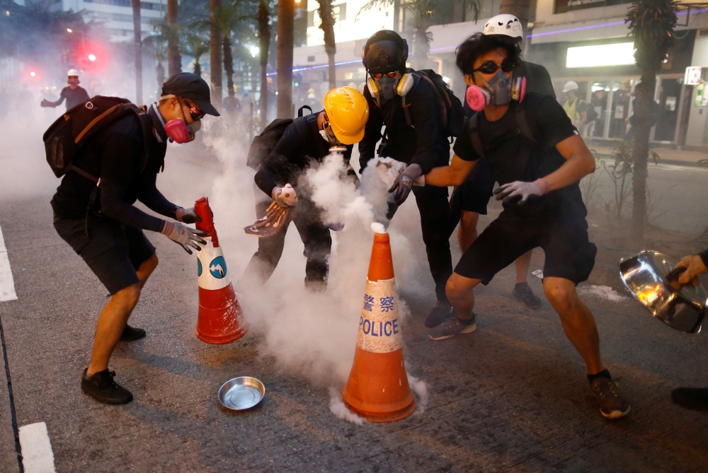 Anti-extradition bill protesters try to extinguish tear gas canisters during a demonstration in Wan Chai neighbourhood in Hong Kong, China, August 11, 2019. (REUTERS/Thomas Peter)