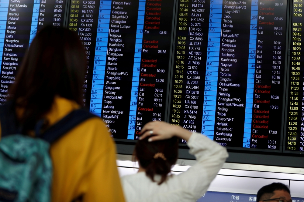 Passengers react as they look at the flight information board as the airport reopened a day after flights were halted due to a protest, at Hong Kong International Airport, China August 13, 2019. REUTERS/Issei Kato