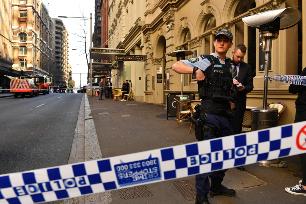 Police gather at the crime scene after a man stabbed a woman and attempted to stab others in central Sydney on August 13, 2019, before being pinned down by members of the public and detained by police.  / AFP / SAEED KHAN