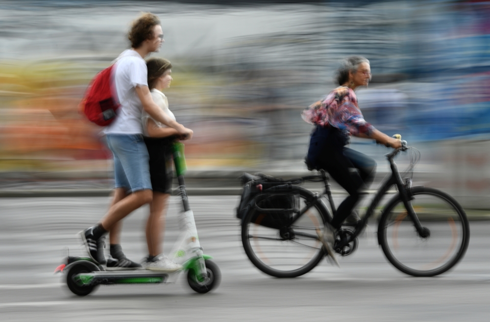 A cyclist passes two people riding an E-Scooter in Berlin, Germany, August 10, 2019. (REUTERS/Annegret Hilse)