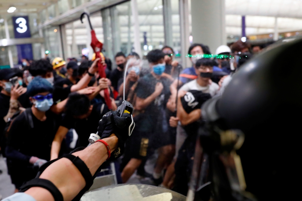 Riot police use pepper spray to disperse anti-extradition bill protesters during a mass demonstration after a woman was shot in the eye, at the Hong Kong international airport, in Hong Kong, China, August 13, 2019. (REUTERS/Tyrone Siu)