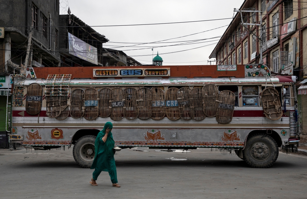 File photo of a Kashmiri woman walks past a bus used as a road block by Indian security personnel during restrictions after the scrapping of the special constitutional status for Kashmir by the government, in Srinagar, August 11, 2019. REUTERS/Danish Sidd