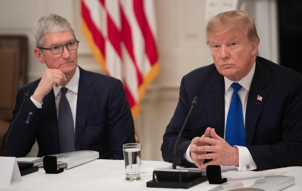 FILE PHOTO: In this file photo taken on March 06, 2019 US President Donald Trump speaks alongside Apple CEO Tim Cook (L) during the first meeting of the American Workforce Policy Advisory Board in the State Dining Room of the White House in Washington, DC