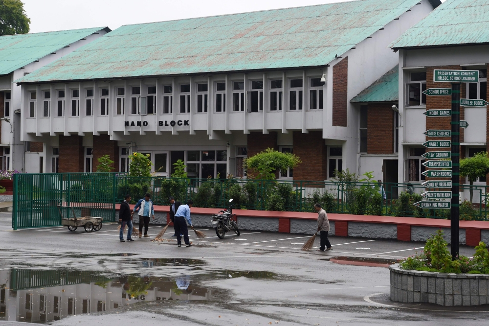 Workers clean the campus of an closed school in Srinagar on August 19, 2019. (AFP / PUNIT PARANJPE)