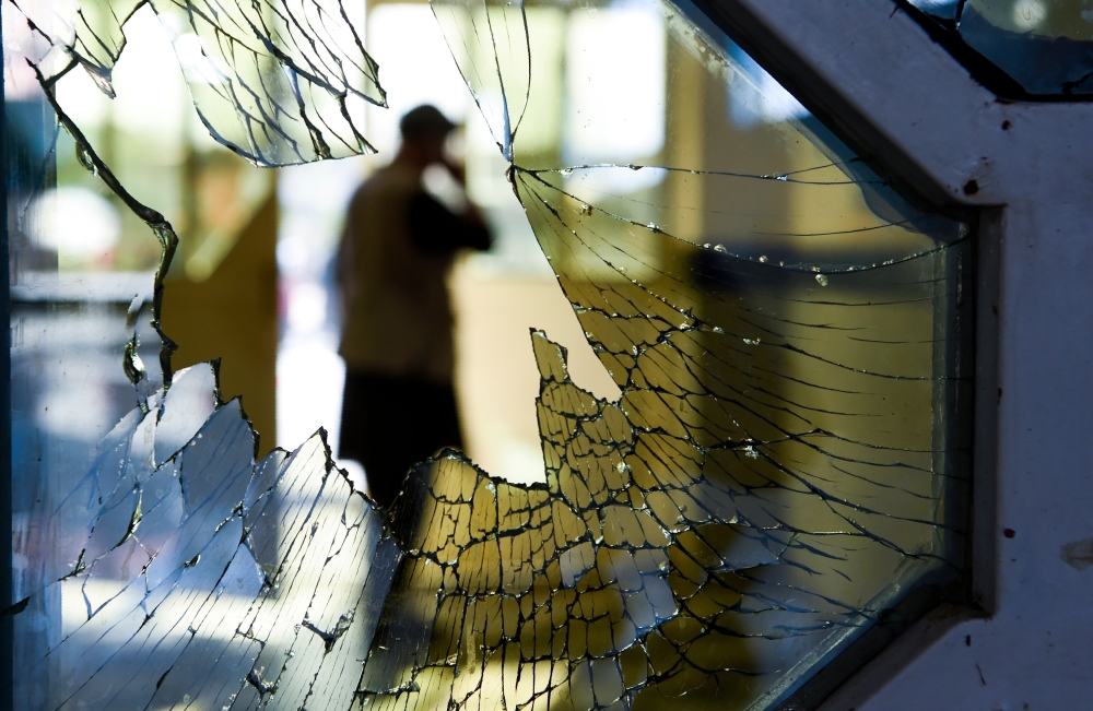 (FILES) In this file photo taken on August 18, 2019, a man is seen through a broken window of a wedding hall after a deadly bomb blast in Kabul. AFP / Wakil Kohsar  