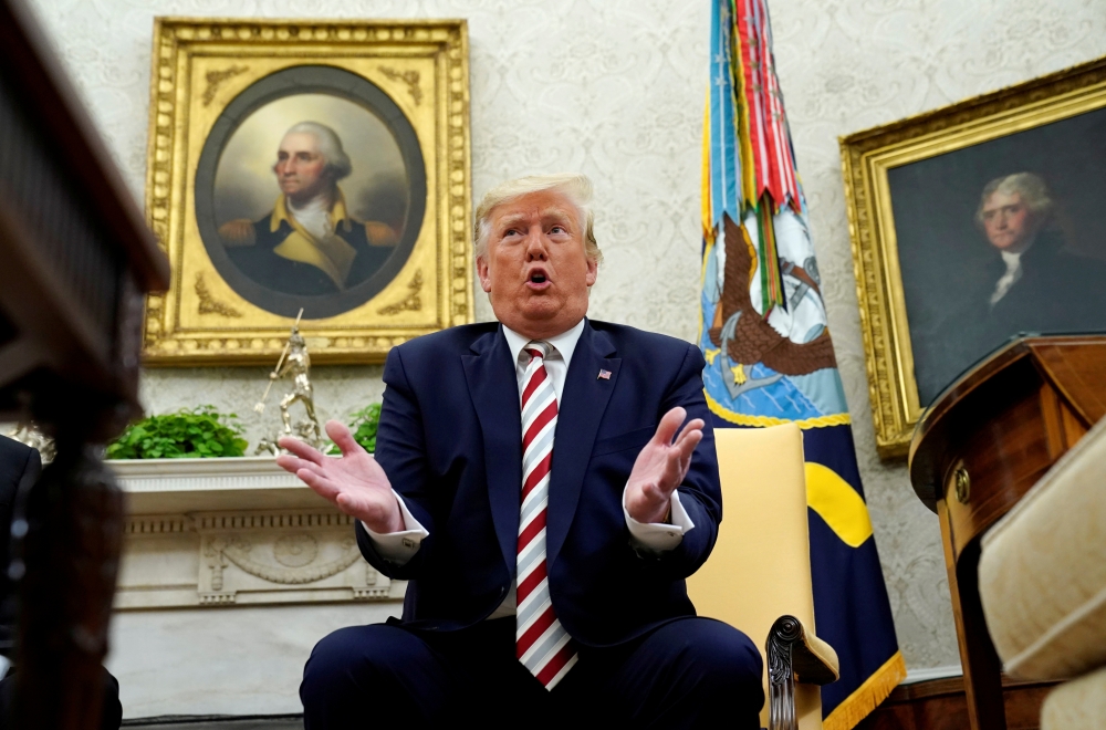U.S. President Donald Trump answers questions while sitting in front of paintings of former U.S. presidents George Washington and Thomas Jefferson during his meeting with Romania's President Klaus Iohannis in the Oval Office of the White House in Washingt