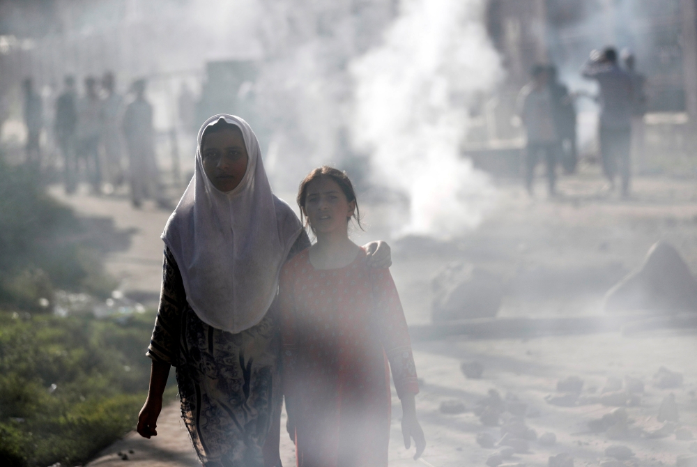 Kashmiri girls walk amidst smoke during clashes between Indian security forces and protestors, after scrapping of the special constitutional status for Kashmir by the Indian government, in Srinagar, August 23, 2019. (REUTERS/Adnan Abidi)