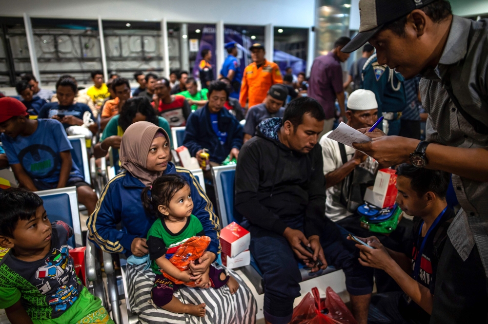 Passengers of a ferry that caught fire gather at Tangjung Perak seaport, after being evacuated, in Surabaya, East Java, on August 23, 2019. AFP / JUNI KRISWANTO