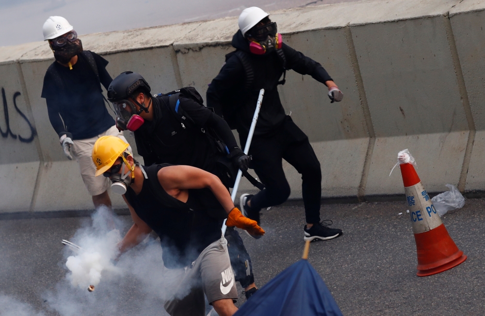 A demonstrator throws back a tear gas canister as they clash with riot police during a protest in Hong Kong, China, August 24, 2019. REUTERS/Kai Pfaffenbach