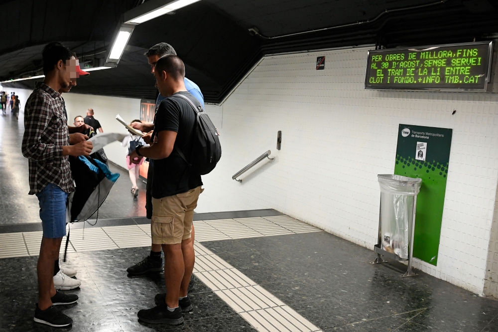 Two police officers in plainclothes check the identification documents of two presumed pickpockets (L) at a metro station in Barcelona on August 14, 2019.  AFP / Lluis Gene
 


. Pictures by Lluis Gene
