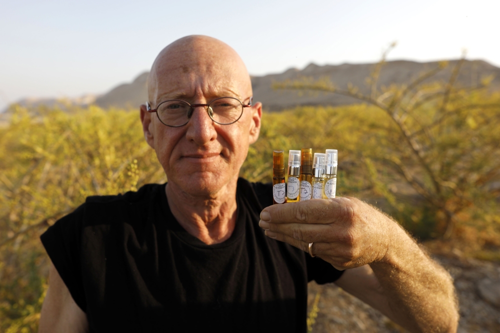 Israeli farmer Guy Erlich shows ampules of scented oils that he extracted from plants and trees at a farm on a small hill near the settlement of Almog in the Israeli-occupied West Bank, on May 28, 2019. AFP / Menahem Kahana
 