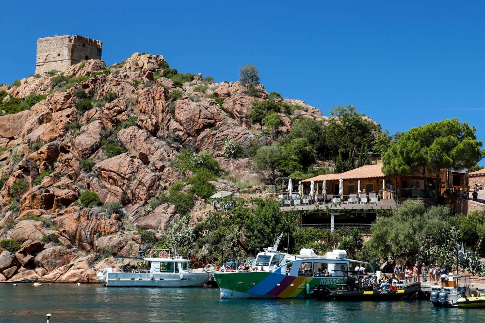 Tourists wait for tour boats on the port of Porto, near Ota, on August 19, 2019, to go on a cruise in the Scandola Nature Reserve, on the western coast of the French Mediterranean island of Corsica. AFP / Pascal Pochard-Casabianca
 