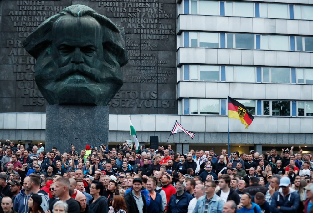 Right-wing demonstrators march past a sculpture of Karl Marx in Chemnitz, eastern Germany, on August 27, 2018, following the death of a 35-year-old German national who died in hospital after a 