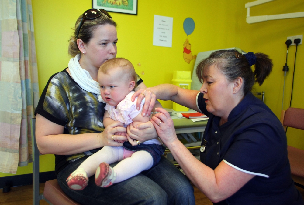  In this file photo taken on April 20, 2013 14-month-old Amelia Down sits on the lap of her mother Helen (L) as she receives the combined Measles Mumps and Rubella (MMR) vaccination at an MMR drop-in clinic at Neath Port Talbot Hospital near Swansea in so