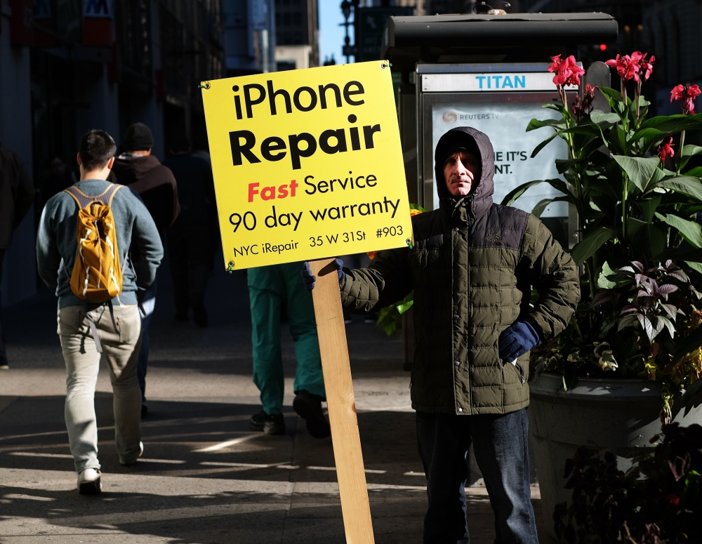 A man displays an advertisement for repairing iPhones in New York on October 19, 2015. AFP / Jewel Samad 