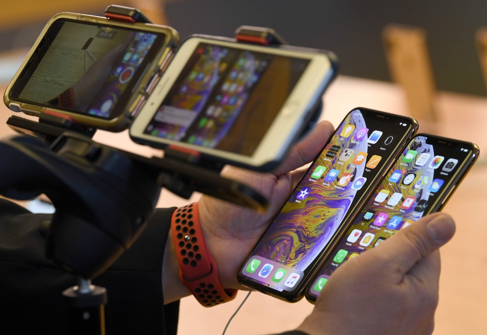 A customer compares the sizes of the latest iPhones at an Apple store in Sydney on September 21, 2018. AFP/Saeed Khan