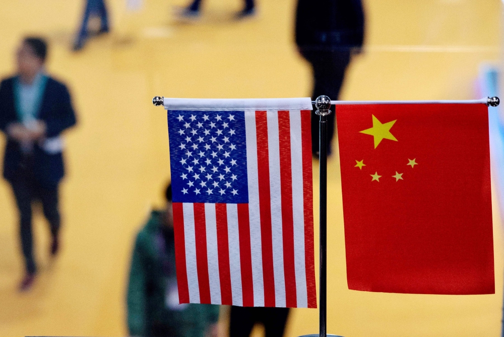 (FILES) This file picture taken on November 6, 2018, shows a Chinese and US flag at a booth during the first China International Import Expo in Shanghai. AFP / Johannes Eisele 