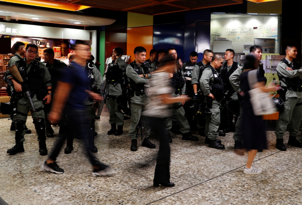 Riot police wait at a Mass Transit Railway (MTR) station as commuters walk past to catch a subway train, in Hong Kong, China, September 2, 2019. REUTERS/Anushree Fadnavis