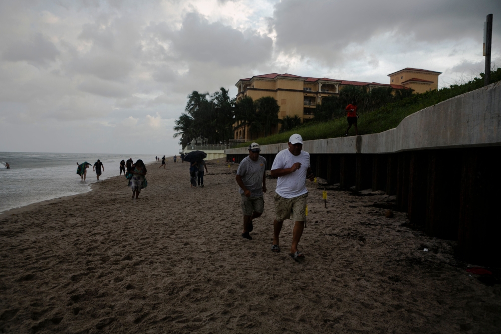 People are seen running from pouring rain on the shore while there are mandatory evacuation orders for parts of Palm Beach County in Lantana Beach, Florida on September 1, 2019. AFP / Eva Marie UZCATEGUI