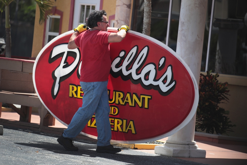A worker removes a sign from the front of a restaurant as Hurricane Dorian continues to make its way toward the Florida coast on September 1, 2019 in Indialantic, Florida. Scott Olson/Getty Images/AFP