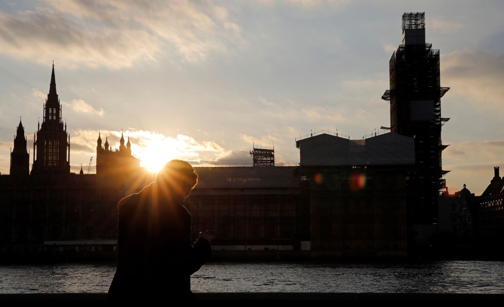 A man stands on the banks of River Thames across from the Houses of Parliament in Westminster in central London, on March 27, 2019. AFP/Tolga Akmen