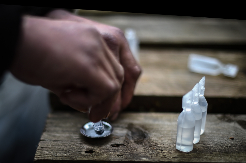 A drug addict prepares cocaine for injection in a small wooded area used by addicts to take drugs near Glasgow city centre, Scotland, on August 15 2019. AFP / Andy Buchanan