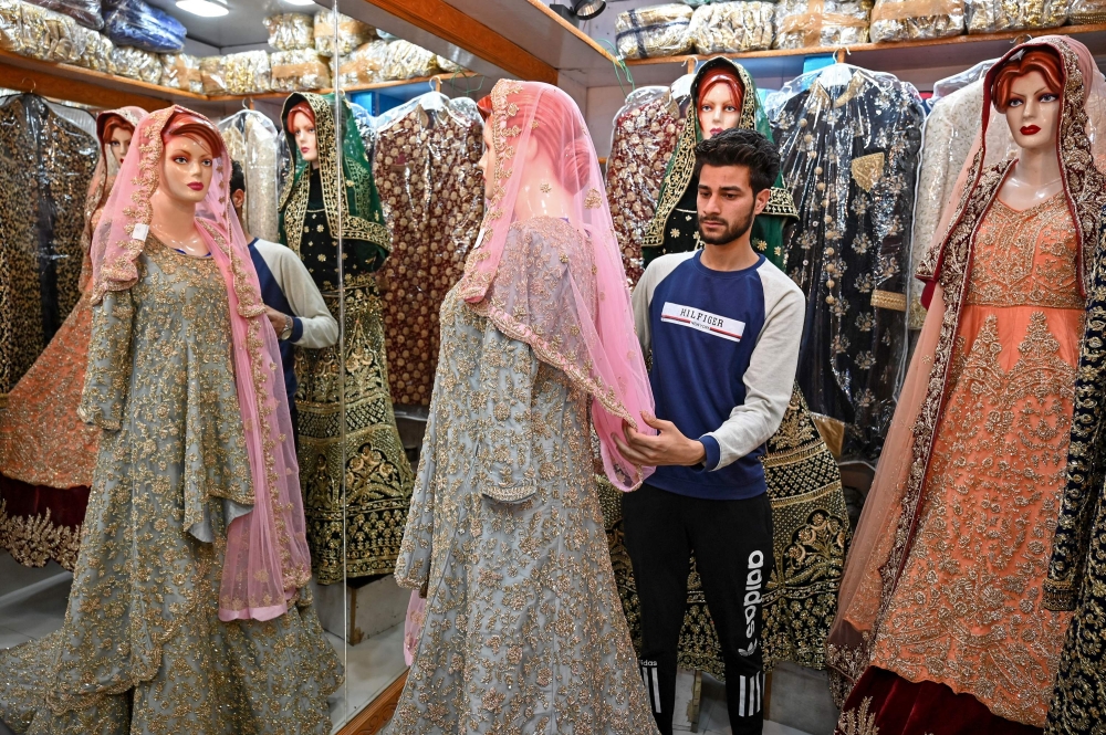 A Kashmiri shopkeeper displays a wedding dress at a market ahead of the Muslim festival of Eid al-Fitr in Srinagar on June 3, 2019. AFP / Tauseef Mustafa