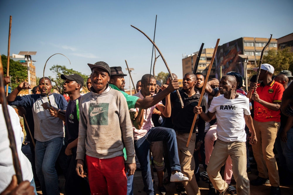 Zulu residents of the Jeppe Men Hostel scream waving batons in the Johannesburg CBD on September 3, 2019, after South Africa's financial capital was hit by a new wave of anti-foreigner violence. AFP / Michele Spatari