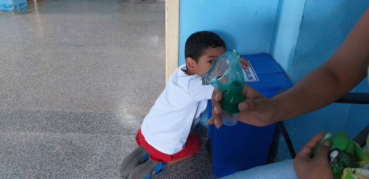 A boy looks on as his mother holds the nebuliser that is helping him with symptons of smoke inhalation, in Porto Velho, Brazil, on August 31, 2019. Thomson Reuters Foundation/Fabio Teixeira