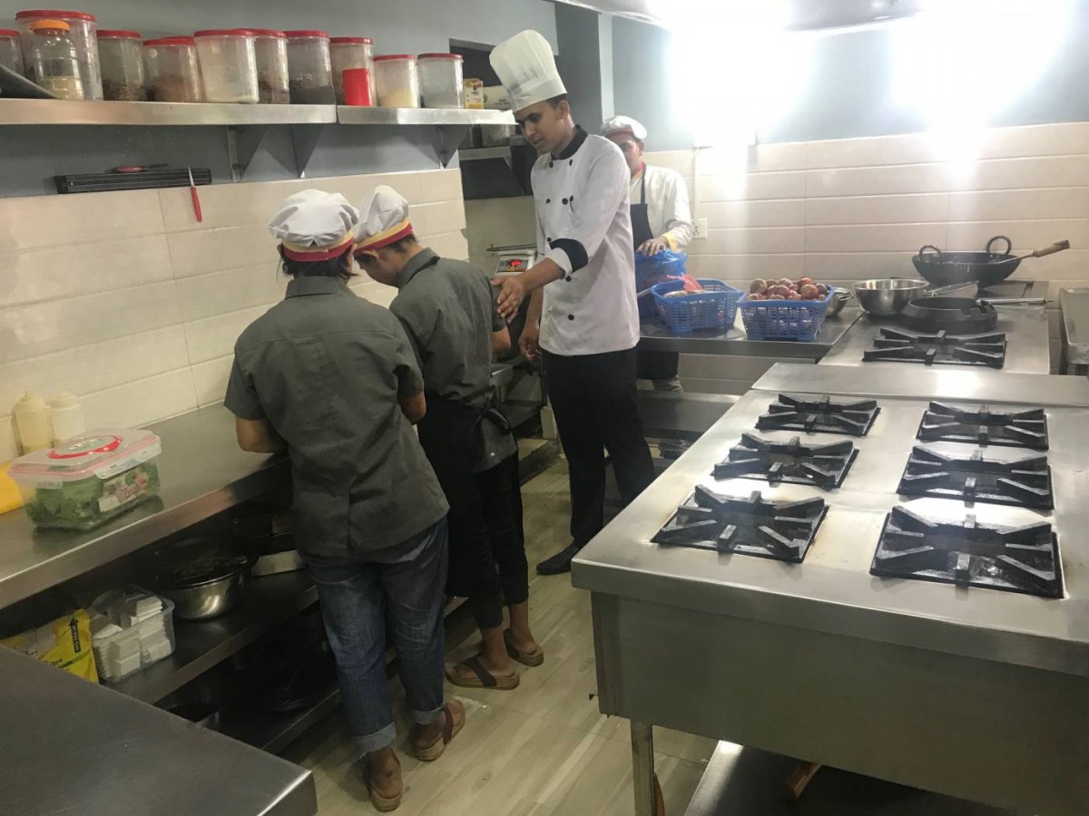 A chef guides two employees - former trafficking victims - in the kitchen of Maiti Cafe in Kathmandu, Nepal, August 16, 2019. Thomson Reuters Foundation/Gopal Sharma