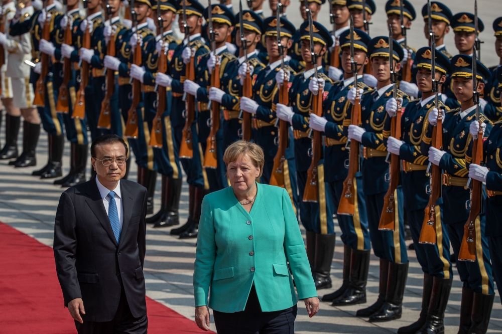 Chinese Premier Li Keqiang (L) and German Chancellor Angela Merkel (C) inspect an honour guard during a welcome ceremony at the Great Hall of the People in Beijing on September 6, 2019. / AFP / POOL / Roman PILIPEY 