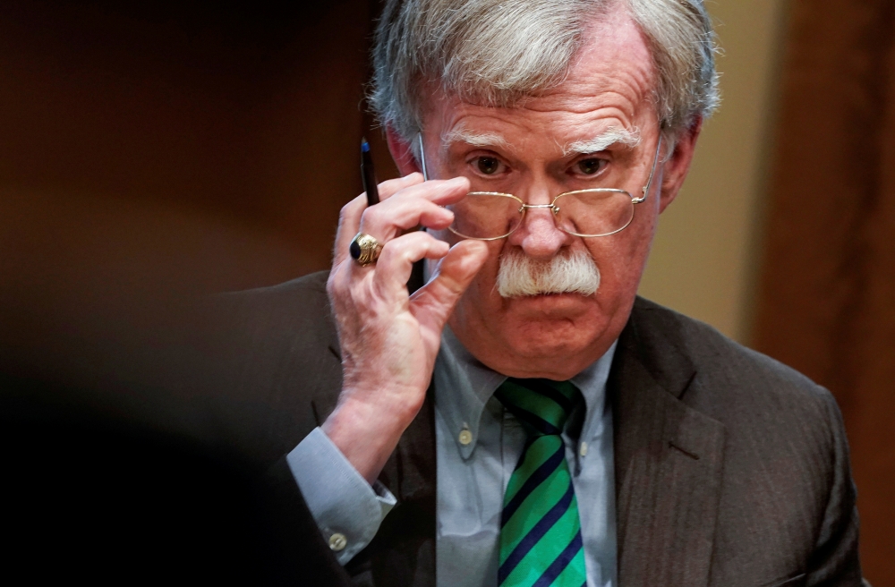 John Bolton adjusts his glasses as US President Donald Trump speaks while meeting with NATO Secretary General Jens Stoltenberg in the Oval Office at the White House, April 2, 2019. Reuters/Joshua Roberts