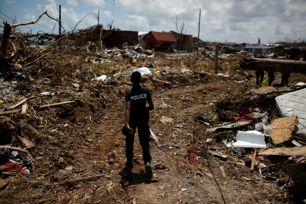 FILE PHOTO: A police officer searches for the dead in the destroyed Mudd neighborhood after Hurricane Dorian hit the Abaco Islands in Marsh Harbour, Bahamas, September 10, 2019. REUTERS/Marco Bello/File Photo