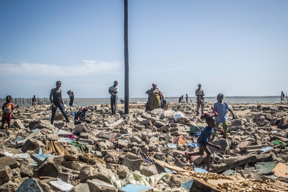 People walk among rubble of demolished houses in Xwlacodji, in the 5th arrondissement of Cotonou on September 3, 2019, after the passage of bulldozers. AFP / Yanick Folly