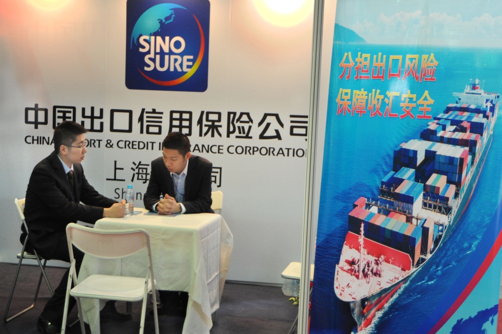Men sit at a booth of China Export and Credit Insurance Corp, known as Sinosure, at the regional trade fair East China Fair in Shanghai, March 1, 2013. Reuters