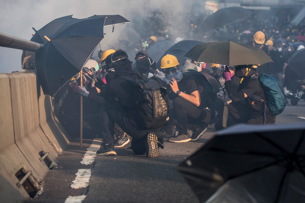 Pro-democracy protesters react after police fired tear gas outside the government headquarters in Hong Kong on September 15, 2019. AFP / Isaac LAWRENCE