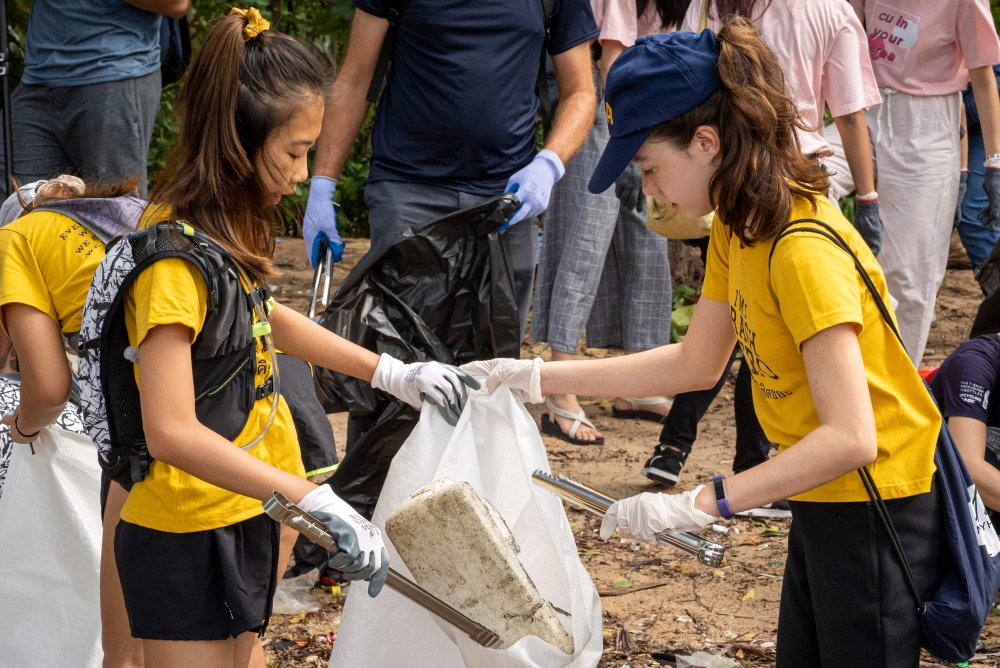 12-year-old Ralyn Satidtanasarn (L), known as Lilly, collects plastic waste during the Trash Hero cleaning initiative at the Khung Bang Kachao urban forest and beach in Bangkok on August 25, 2019.  AFP / Mladen Antonov
