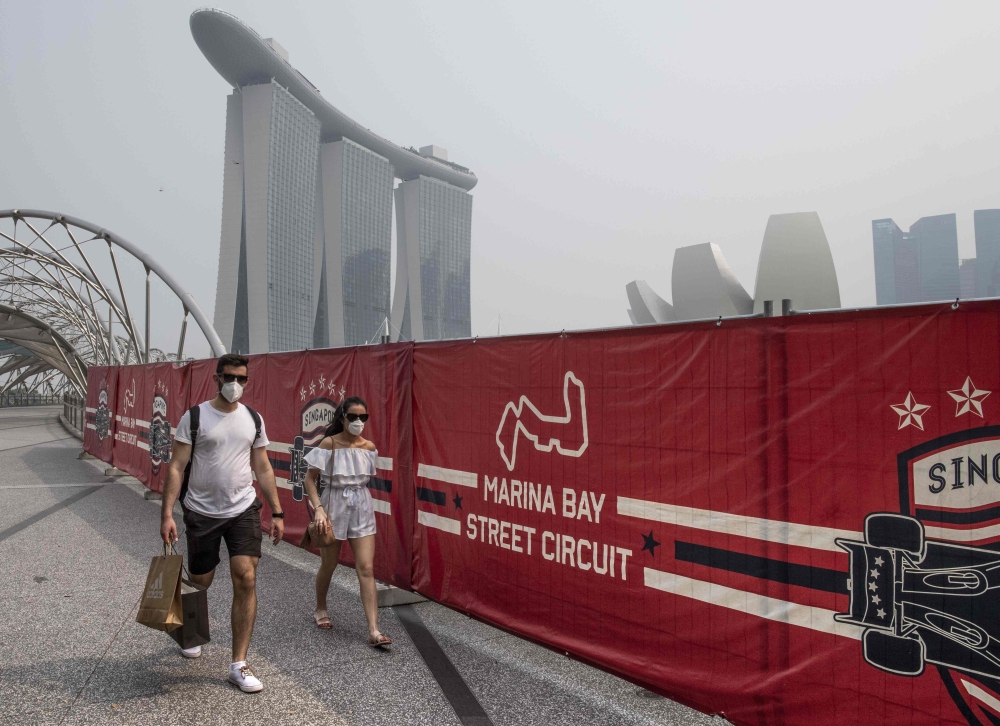 Tourists wear protective masks as they walk near the Formula One Singapore Grand Prix night race track while haze blankets Singapore on September 18, 2019. AFP / Mladen ANTONOV