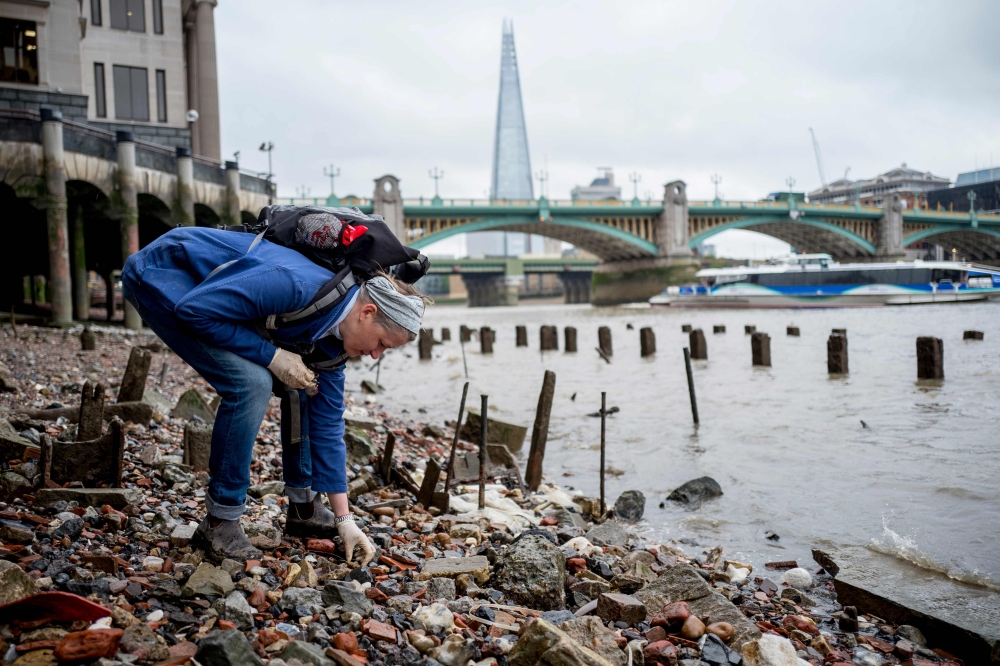 Lara Maiklem, a mudlark searches for treasure at low tide along the river Thames in central London on May 29, 2019. AFP / Tolga Akmen 