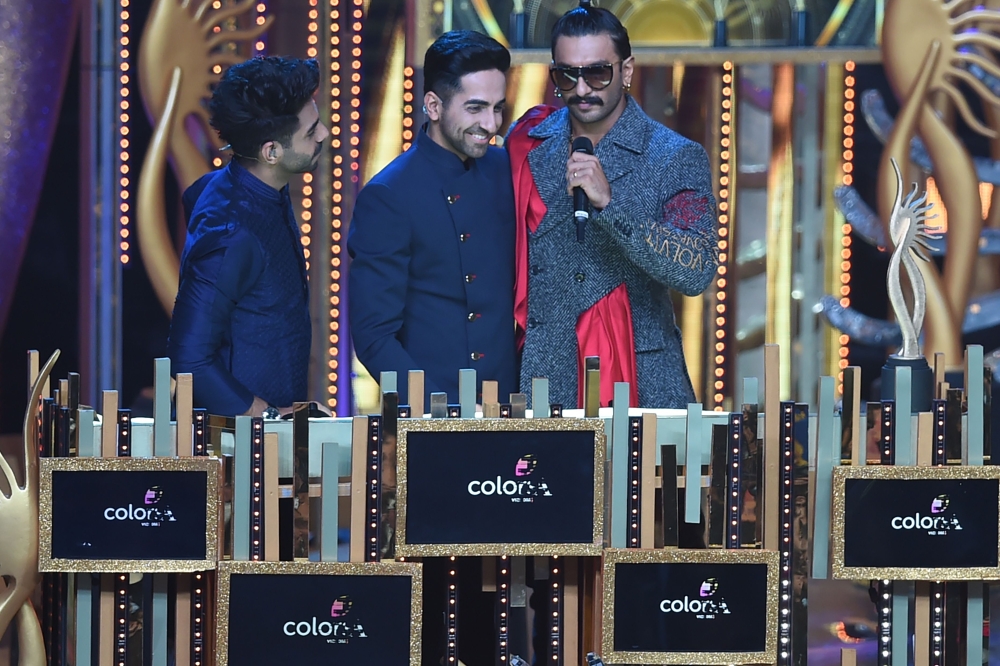 Bollywood actor Aparshakti Khurrana (L) looks on as his brother Ayushmann Khurrana (C) and actor Ranveer Singh interact on stage during the 20th International Indian Film Academy (IIFA) Awards at NSCI Dome in Mumbai on September 18, 2019. / AFP / INDRANIL