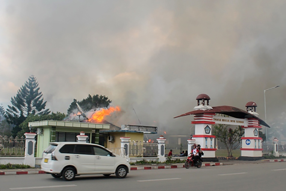 A car passes governor office building of Jayawijaya burned during a protest in Wamena, Papua, Indonesia, September 23, 2019 in this photo taken by Antara Foto. Antara Foto/Marius Wonyewun/ via REUTERS 