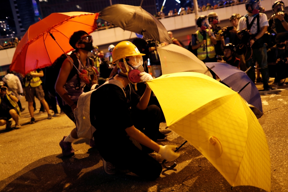An anti-government protester shelters behind an umbrella as he attends a rally outside the Legislative Council building in Hong Kong, China September 28, 2019. REUTERS/Jorge Silva