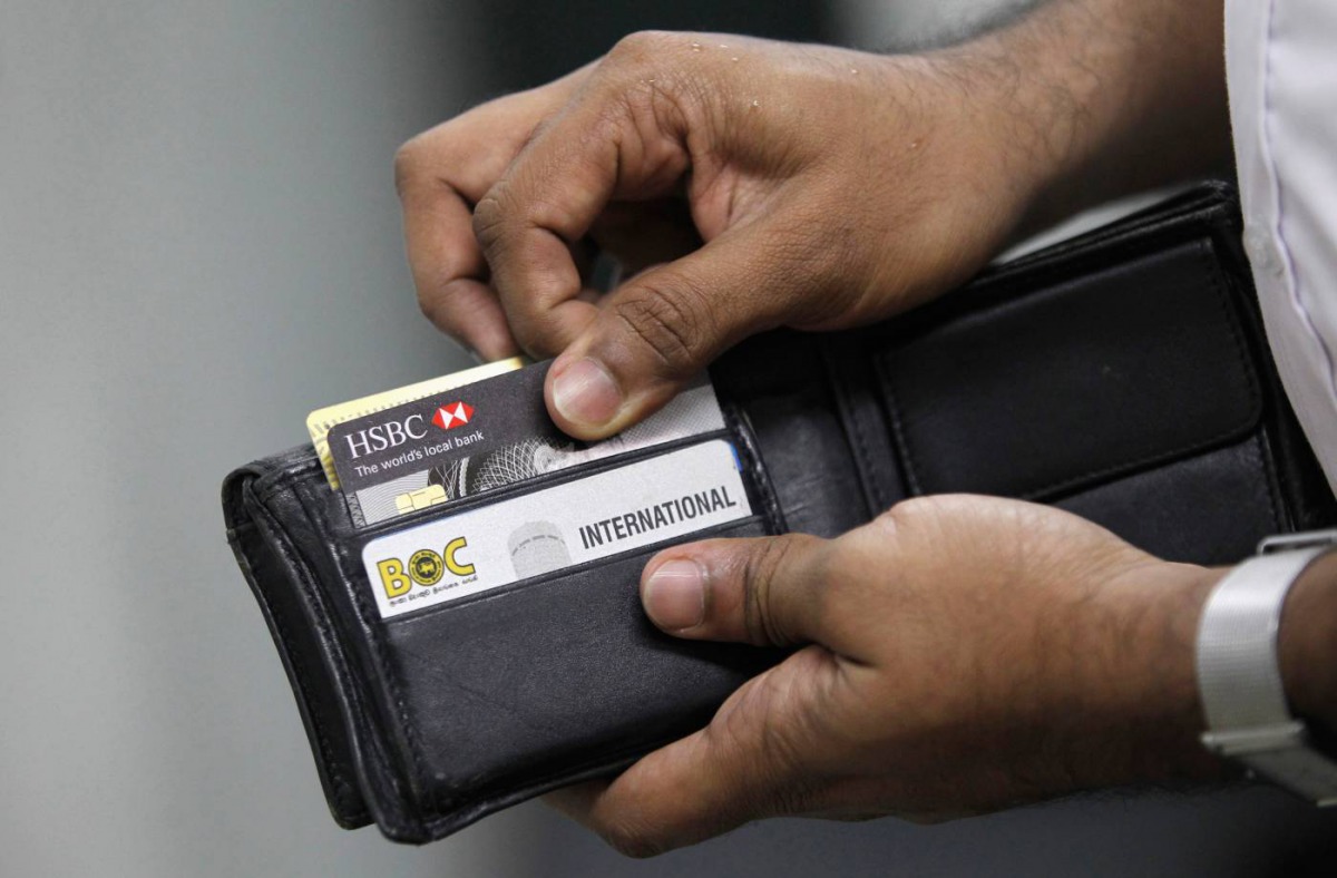 A man pulls out his credit card to make a purchase at a shop in Colombo June 11, 2013. Reuters/Dinuka Liyanawatte