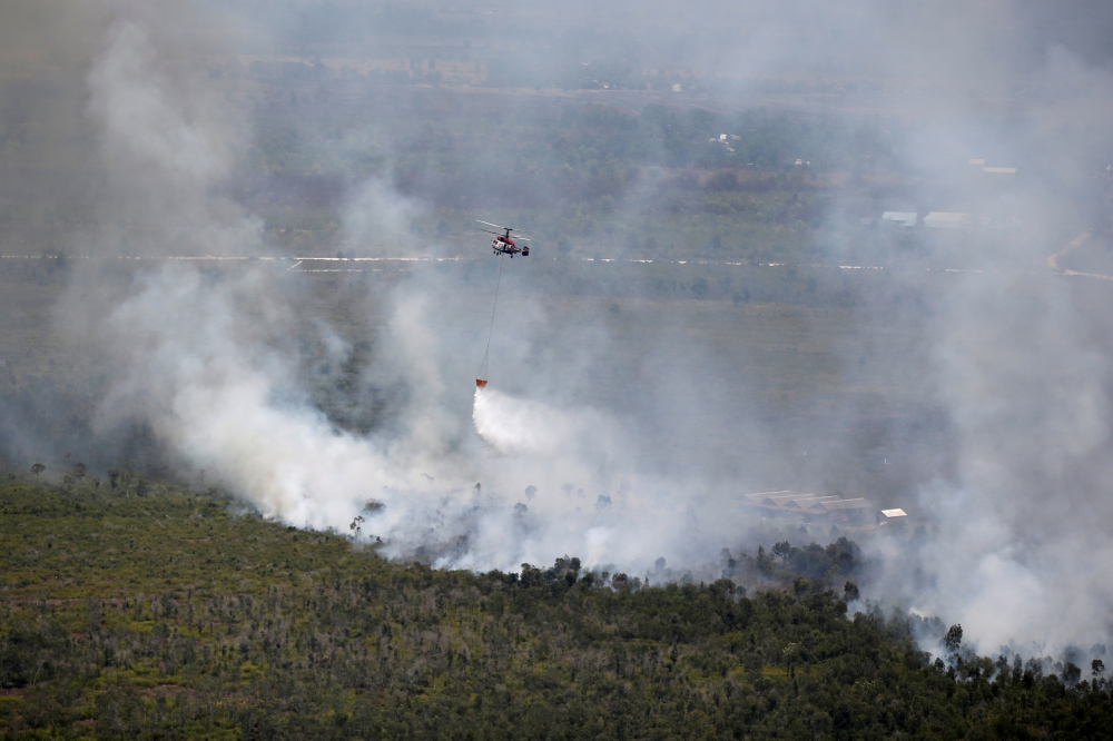 An Indonesian National Disaster Management Agency (BNPB) helicopter dumps water on a burning forest near Banjarmasin in South Kalimantan province, Indonesia, September 29, 2019. REUTERS/Willy Kurniawan 